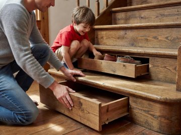 Person pulling open a concealed timber drawer built directly into the bottom two steps of a staircase